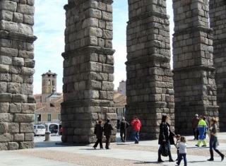 personas paseando por debajo del acueducto de segovia